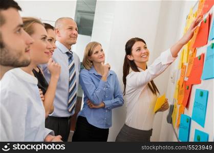 Businesswoman pointing on whiteboard in meeting with office colleagues