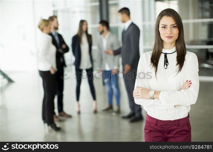 Businesswoman posing while others business people talking in background