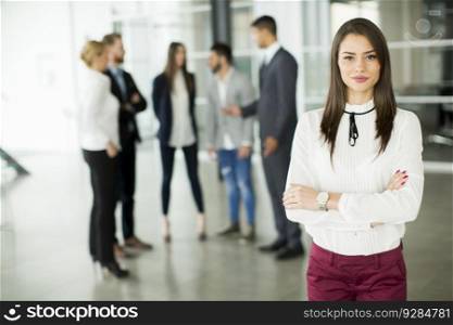 Businesswoman posing while others business people talking in background