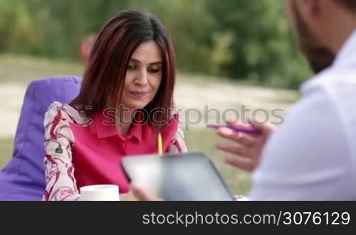 Businesswoman presenting business plan to partner during business lunch outdoors