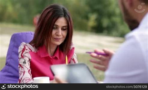 Businesswoman presenting business plan to partner during business lunch outdoors