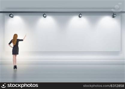 Businesswoman pressing virtual button on the wall lit with spotlights. Businesswoman pressing virtual button on the wall lit with spotl