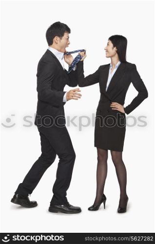 Businesswoman pulling businessman&rsquo;s tie