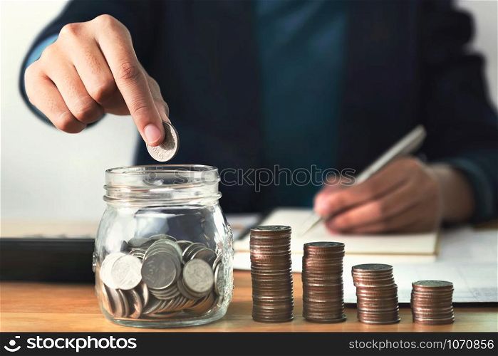 businesswoman putting coins in glass. concept saving money and finance accounting