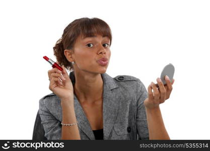 Businesswoman putting on red lipstick