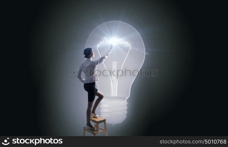 Businesswoman reaching idea. Back view of businesswoman standing on chair and reaching light bulb