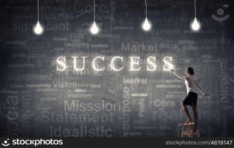 Businesswoman reaching success. Back view of businesswoman standing on chair and reaching light bulb