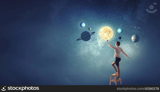 Businesswoman reaching success. Businesswoman standing on chair and reaching planets