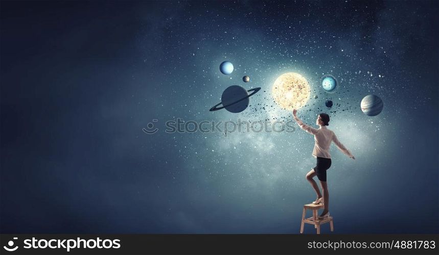Businesswoman reaching success. Businesswoman standing on chair and reaching planets