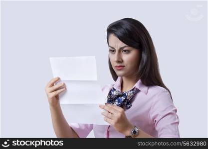 Businesswoman reading document over gray background
