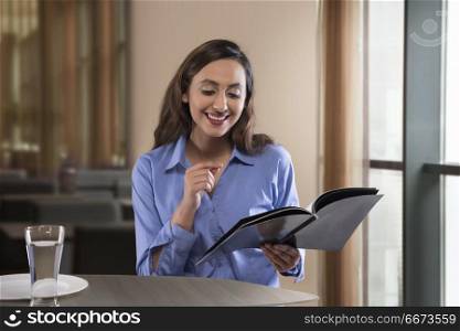 Businesswoman reading magazine on table