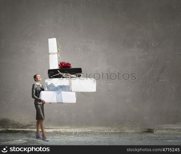 Businesswoman receiving or presenting gift. Attractive businesswoman carrying big gift box in her hands