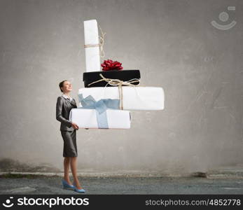 Businesswoman receiving or presenting gifts. Attractive businesswoman and pile of gift boxes in her hands