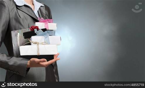 Businesswoman receiving or presenting gifts. Close view of businesswoman and pile of gift boxes in her hand