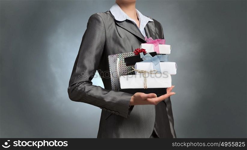Businesswoman receiving or presenting gifts. Close view of businesswoman and pile of gift boxes in her hand