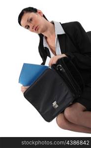 Businesswoman removing paperwork from bag
