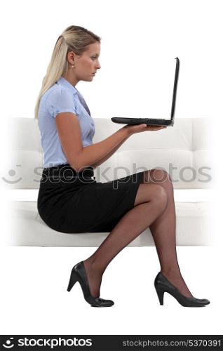 Businesswoman sat on sofa with laptop