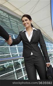 Businesswoman shaking hands with businessman outdoors