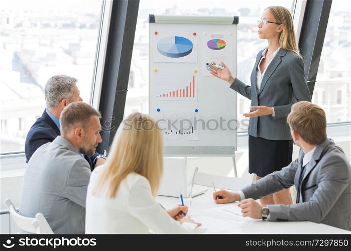 Businesswoman show graph at flichart to business people group on presentation at conference meeting. Business woman show graph