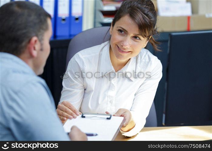 businesswoman showing clipboard to client during meeting