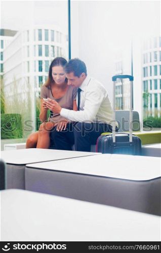 Businesswoman showing smartphone with businessman in hotel lobby