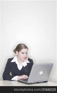 Businesswoman sitting at a table next to her laptop being bored with her day