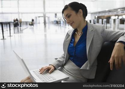 Businesswoman sitting at an airport and using a laptop