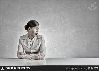 Businesswoman sitting at desk. Emotional attractive businesswoman sitting at table in office