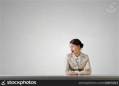 Businesswoman sitting at desk. Emotional attractive businesswoman sitting at table in office