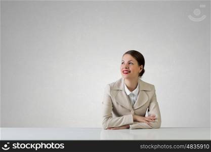 Businesswoman sitting at desk. Happy attractive businesswoman sitting at table in office