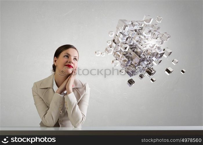 Businesswoman sitting at desk. Happy attractive businesswoman sitting at table in office and 3D rendering cube figure