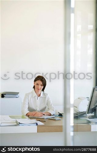 Businesswoman sitting at desk in office front view.