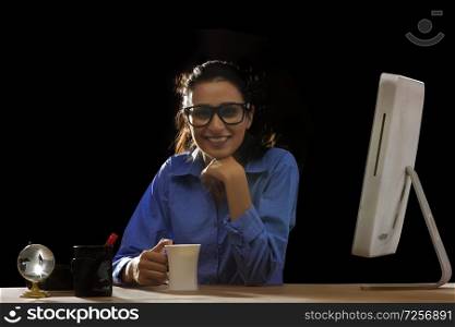 Businesswoman sitting at desk in office, holding mug