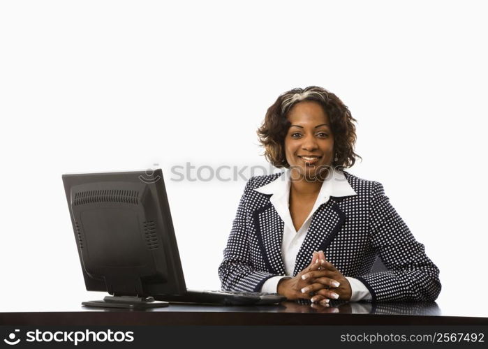 Businesswoman sitting at desk with computer smiling.