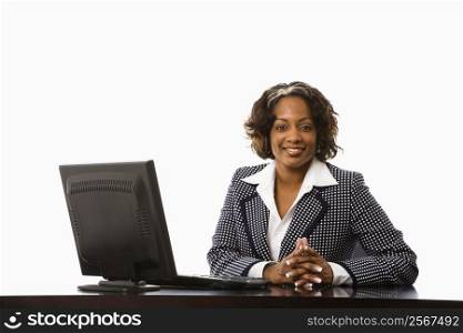 Businesswoman sitting at desk with computer smiling.