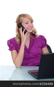 businesswoman sitting at her desk and talking on the phone