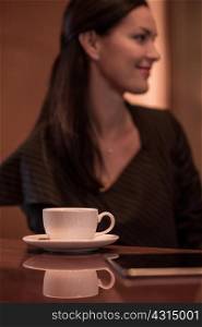 Businesswoman sitting at hotel bar with coffee and digital tablet
