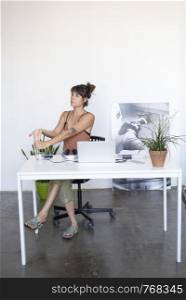 Businesswoman sitting at the table in office and stretching her hands. Rafa Fernandez