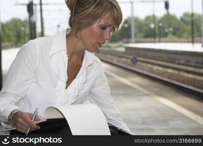 Businesswoman sitting at the trainstation checking her feet that have been in high heels all day
