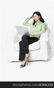 Businesswoman sitting in an armchair and using a laptop