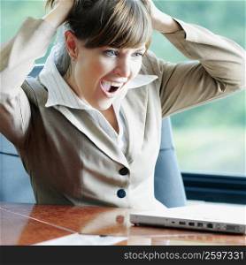 Businesswoman sitting in front of a laptop and pulling her hair