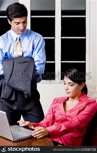 Businesswoman sitting in front of a laptop with a businessman looking at her