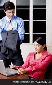 Businesswoman sitting in front of a laptop with a businessman looking at her