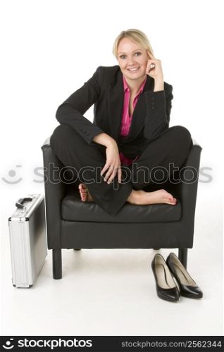 Businesswoman Sitting In Leather Chair With Her Shoes Off