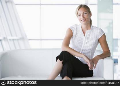 Businesswoman sitting in office lobby smiling