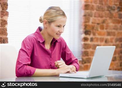 Businesswoman sitting in office using laptop smiling