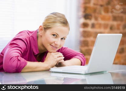 Businesswoman sitting in office with laptop smiling