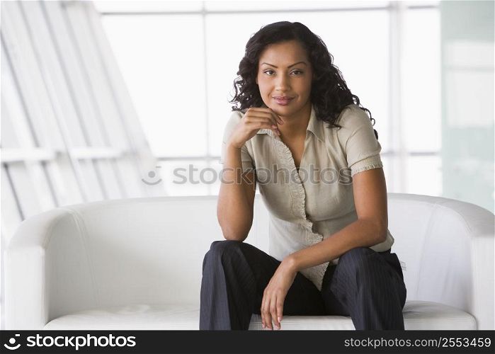 Businesswoman sitting indoors smiling (high key/selective focus)