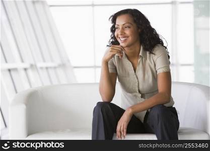 Businesswoman sitting indoors smiling (high key/selective focus)