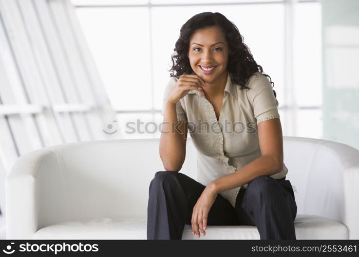 Businesswoman sitting indoors smiling (high key/selective focus)